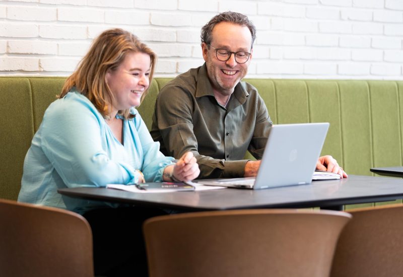 Francesco en Sandra van Flow Accountants zitten lachend achter een laptop